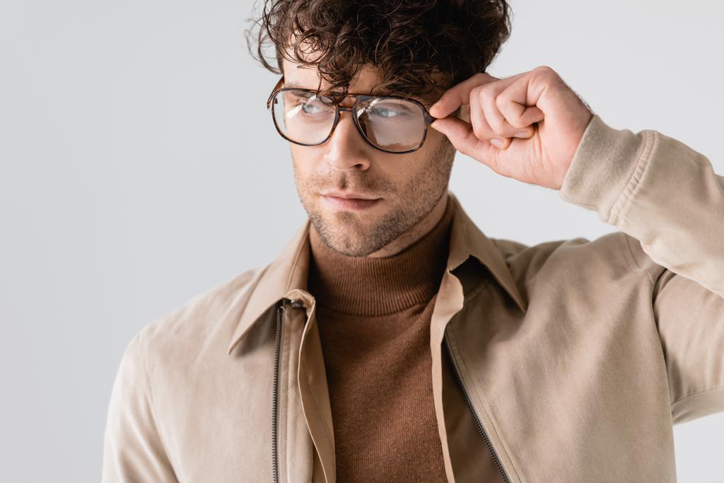 bonito, homem elegante tocando óculos enquanto olhando para longe isolado em cinza
 - Foto, Imagem