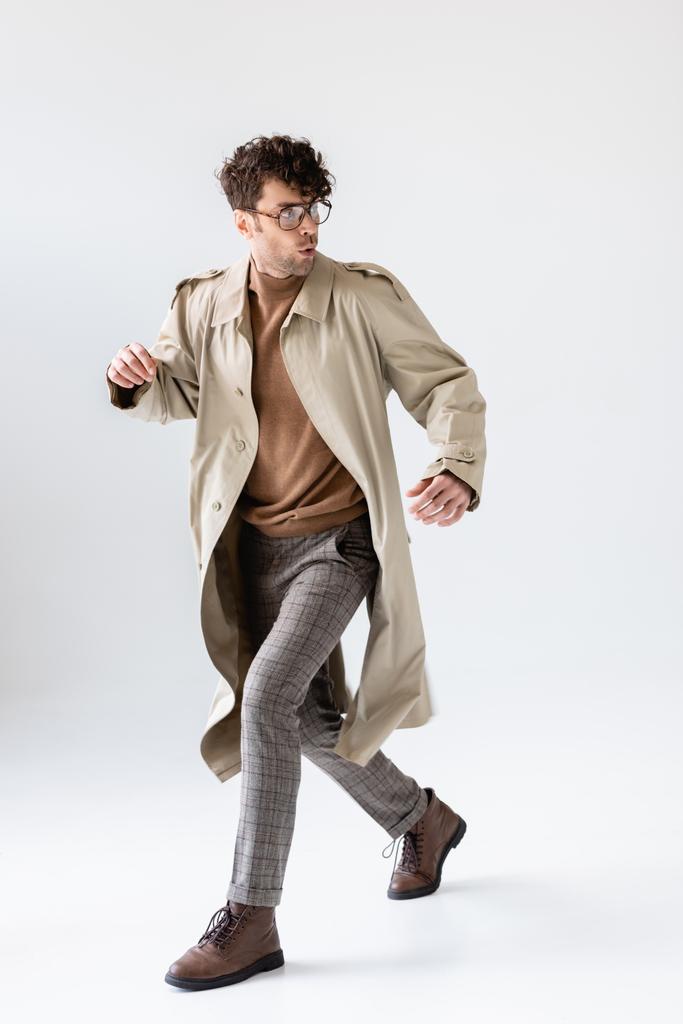 hombre de moda, asustado corriendo y mirando hacia atrás aislado en gris
 - Foto, Imagen