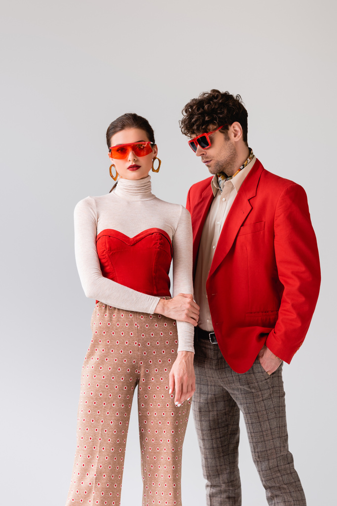 alla moda giovane coppia in occhiali da sole posa isolata su grigio - Foto, immagini