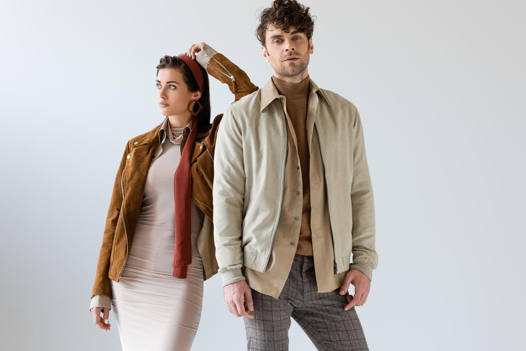 Attractive woman looking away and leaning on handsome man in autumn outfit on grey  - Photo, Image