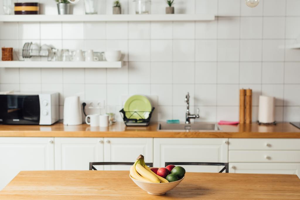 Frische Früchte in Schüssel auf Holztisch in Küche  - Foto, Bild
