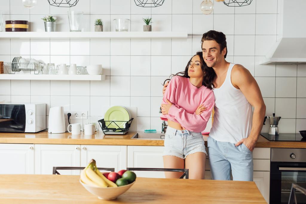 foyer sélectif de sourire homme étreignant belle femme près du plan de travail dans la cuisine  - Photo, image