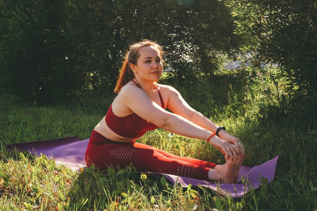 mladá krásná žena v červených kamaších a top cvičení jógy v městském parku - Fotografie, Obrázek