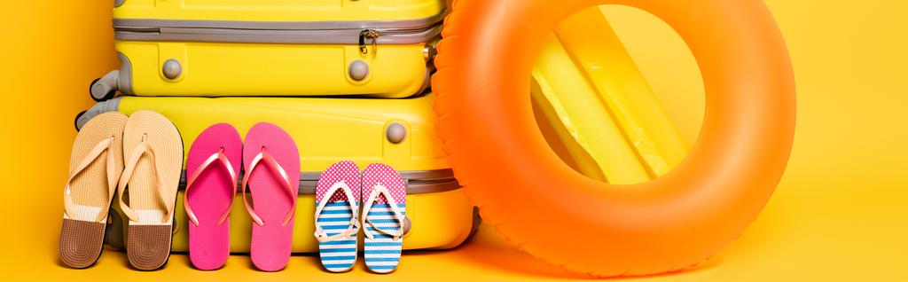 sacs de voyage avec des tongs familiales et des flotteurs de piscine sur jaune, panoramique - Photo, image