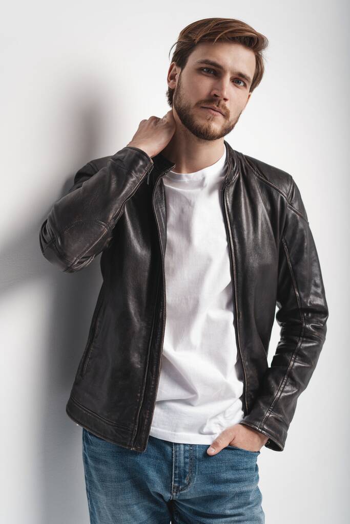 Fashion man, Handsome serious beauty male model portrait wear leather jacket, young guy over white background. - Photo, Image