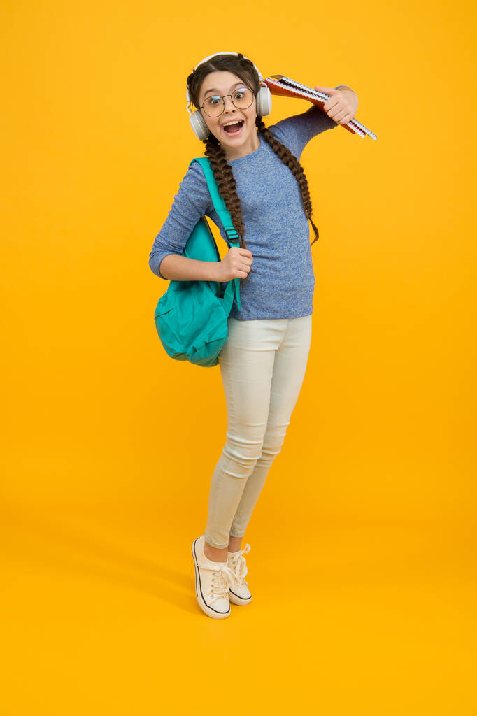 С возвращением в школу. Счастливый ребенок носить рюкзак желтый фон. Девочка вернулась к учебе. Возвращайся в класс. Школа и образование. 1 сентября. День знаний. Частное обучение. Возвращение в школу - Фото, изображение