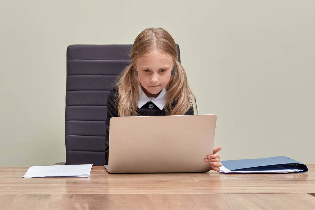 Симпатичная девушка сосредоточенно работает в офисе с ноутбуком. Рабочий процесс. - Фото, изображение