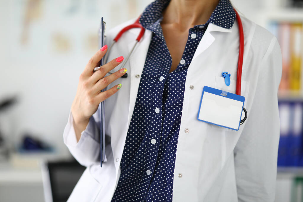 Femme médecin avec stéthoscope tient presse-papiers dans ses mains. - Photo, image