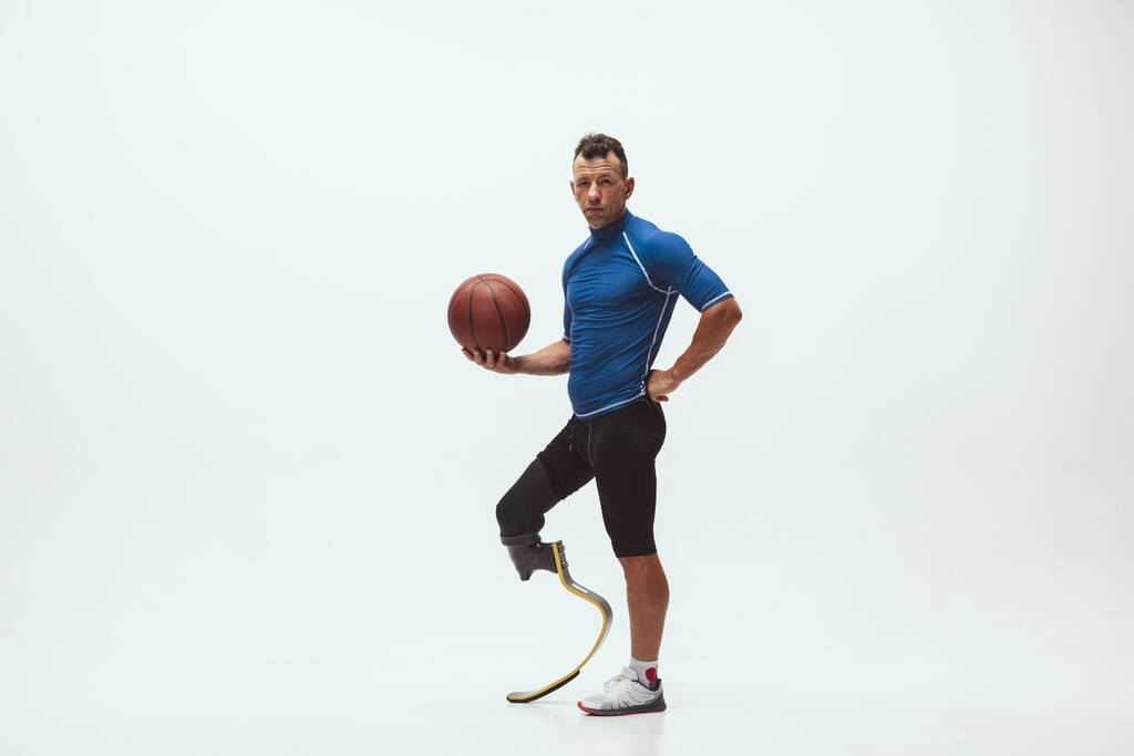 Sportler mit Behinderungen oder amputiert isoliert auf weißem Studiohintergrund. Basketballprofi mit Beinprothese trainiert und übt im Studio. - Foto, Bild