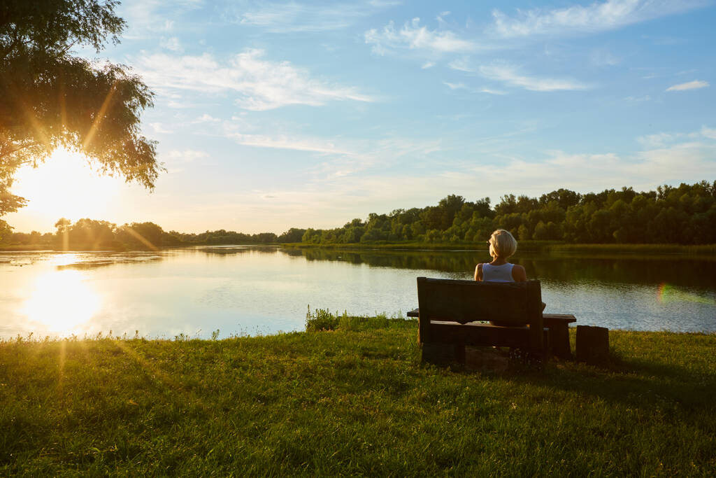 Žena sedí na lavičce během krásného západu slunce - Fotografie, Obrázek