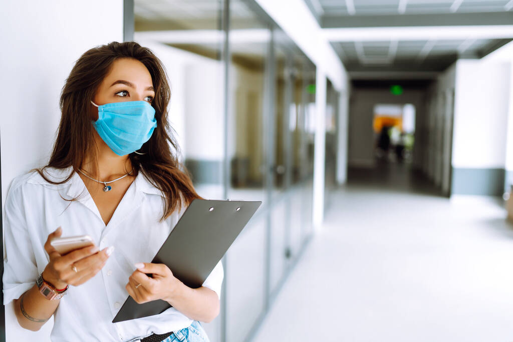 Travailleuse de bureau en masque stérile travaille au bureau pendant une épidémie. COVID-19. Concept d'entreprise.  - Photo, image