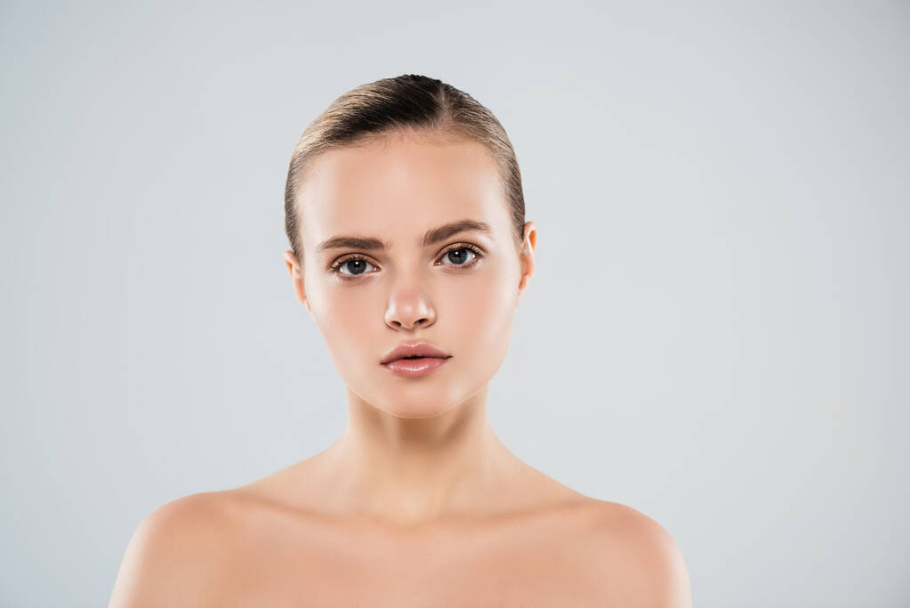 nackte junge Frau blickt vereinzelt in die Kamera auf grau - Foto, Bild