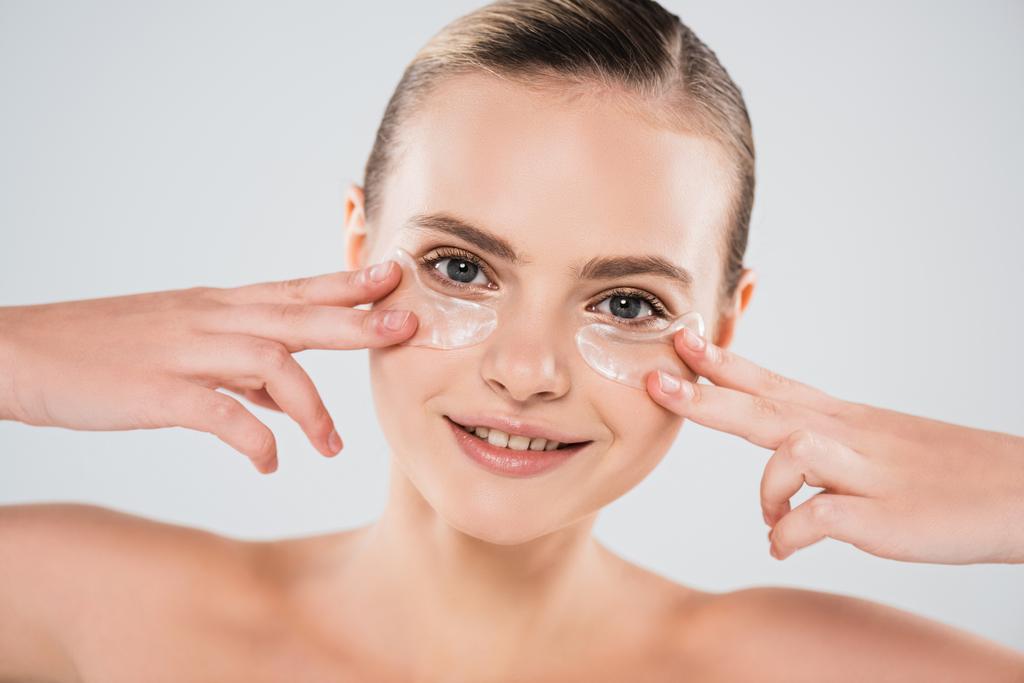 smiling and naked woman touching eye patches isolated on grey - Photo, Image