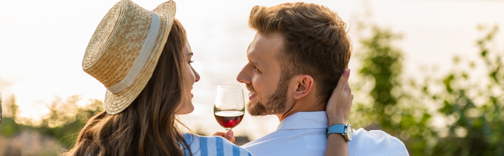 panoraama sato iloinen nainen olki hattu koskettaa onnellinen poikaystävä lasin lähellä punaviiniä  - Valokuva, kuva