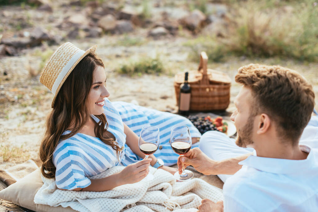 foyer sélectif de femme heureuse en chapeau de paille et homme barbu tenant des verres avec du vin rouge  - Photo, image