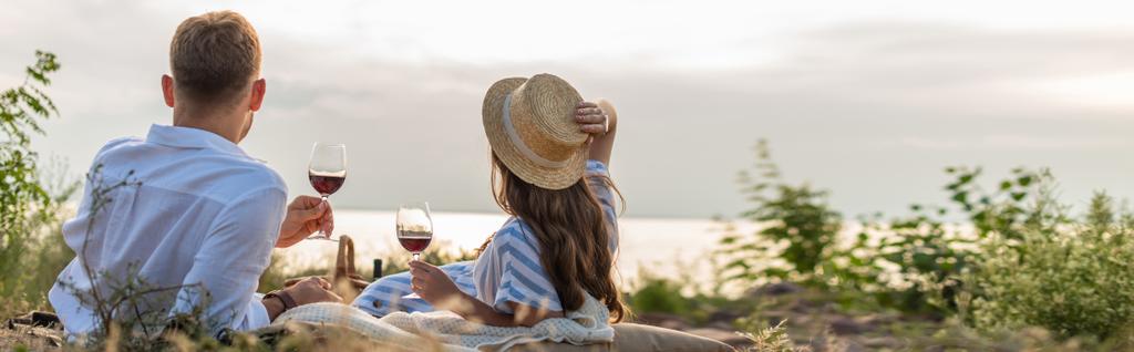 horizontal concept of couple holding glasses with red wine outside  - Photo, Image