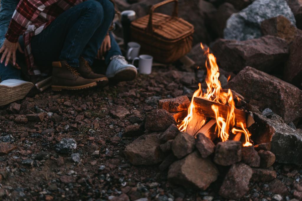 επιλεκτική εστίαση της καύσης της φωτιάς κοντά σε ζευγάρι κάθεται σε βράχους - Φωτογραφία, εικόνα