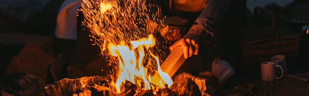 cultura panorâmica do homem colocando log na fogueira perto da menina
  - Foto, Imagem
