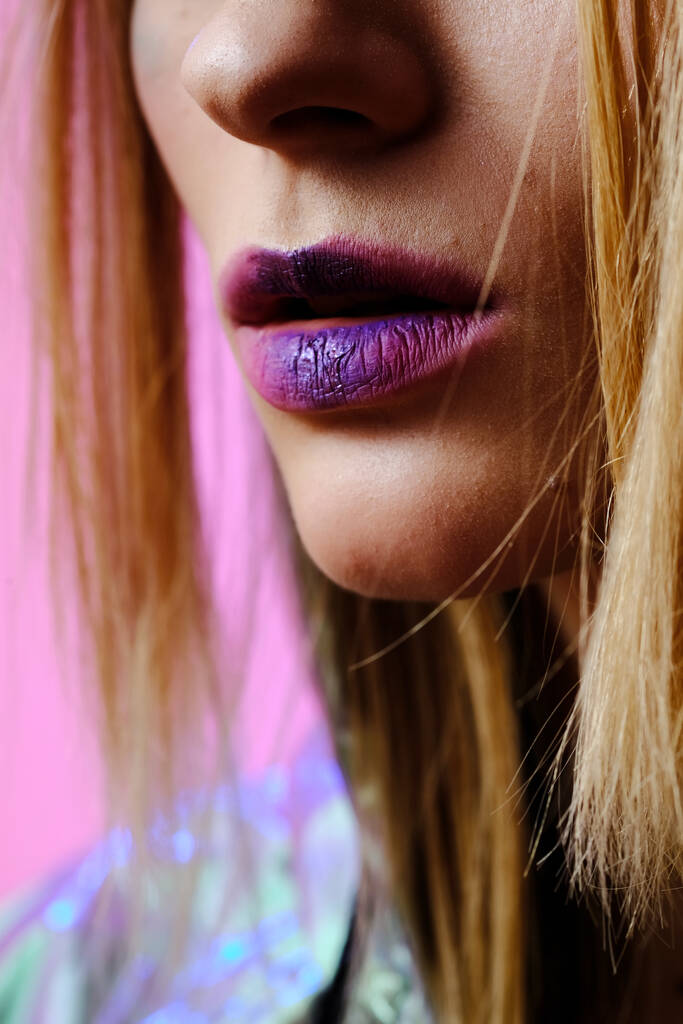 Primo piano di labbra femminili con rossetto lucente. Trucco nelle tonalità rosa e viola. - Foto, immagini
