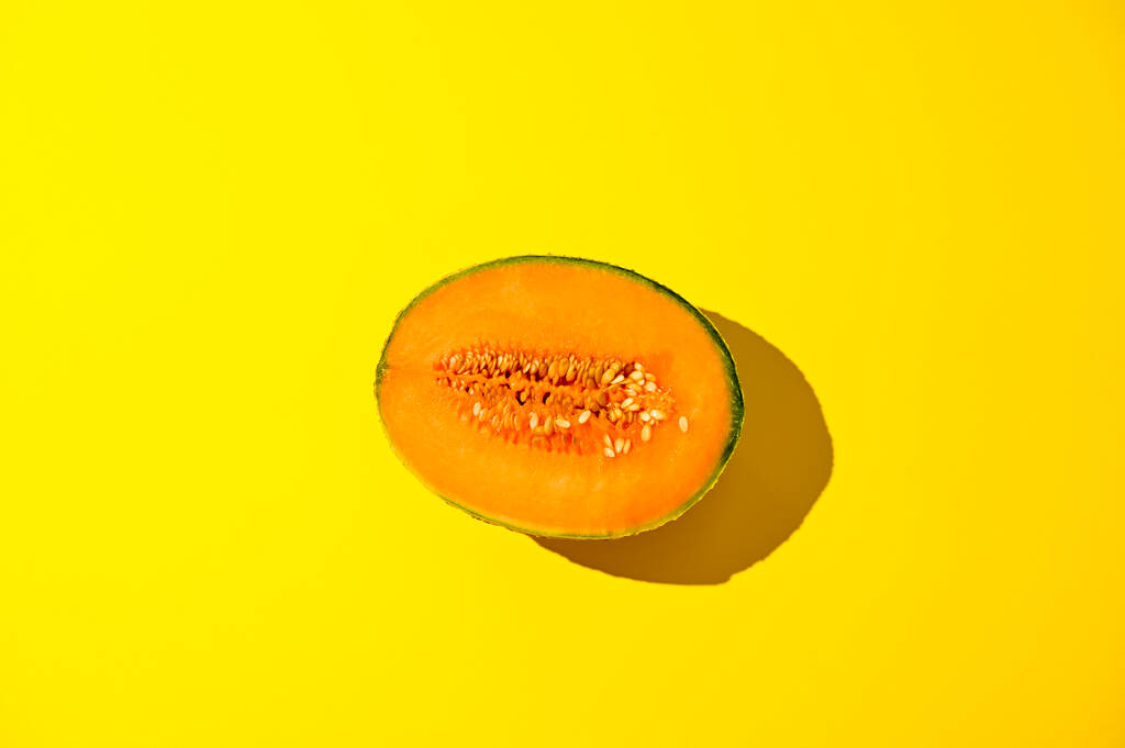 Melone in forte luce solare su fondo giallo. Succosa frutta estiva matura. Spazio libero per il testo. - Foto, immagini