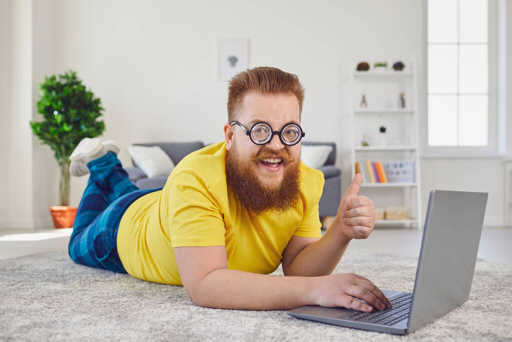 Работа онлайн в домашнем офисе. Забавный человек работает онлайн общаться видео чата с помощью ноутбука, лежащего на полу дома. - Фото, изображение