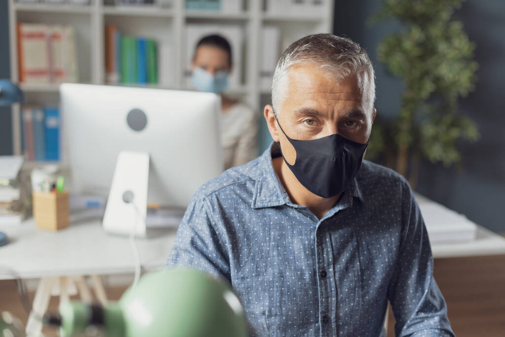 Prevención del Coronavirus y distanciamiento social en la oficina: gente de negocios que mantiene la distancia de seguridad y lleva una máscara facial, concepto de prevención del coronavirus
 - Foto, imagen
