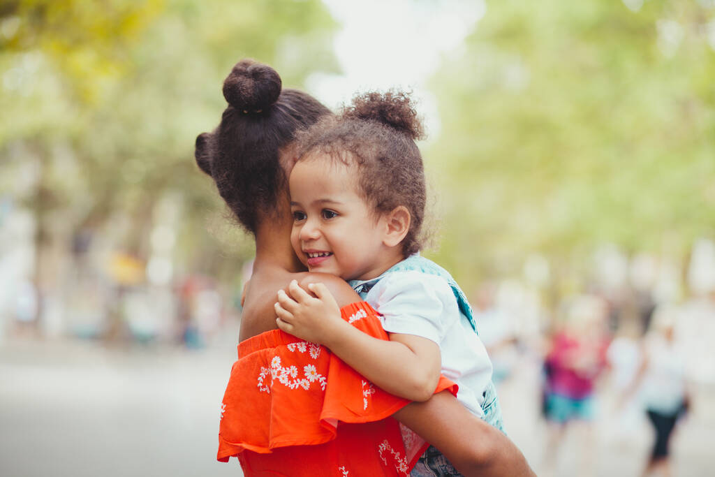 Büyük abla sokakta kucağında küçük kız kardeşine sarılıyor. - Fotoğraf, Görsel