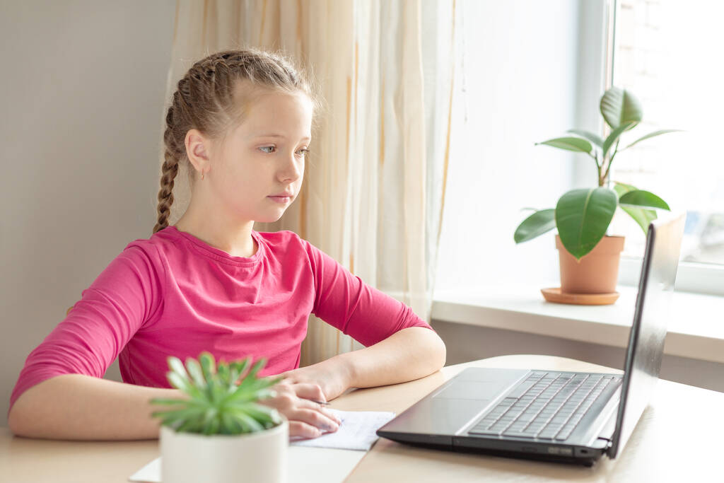 Школьная девушка сидит за столом и пользуется ноутбуком дома. Возвращение в школу - Образ - Фото, изображение