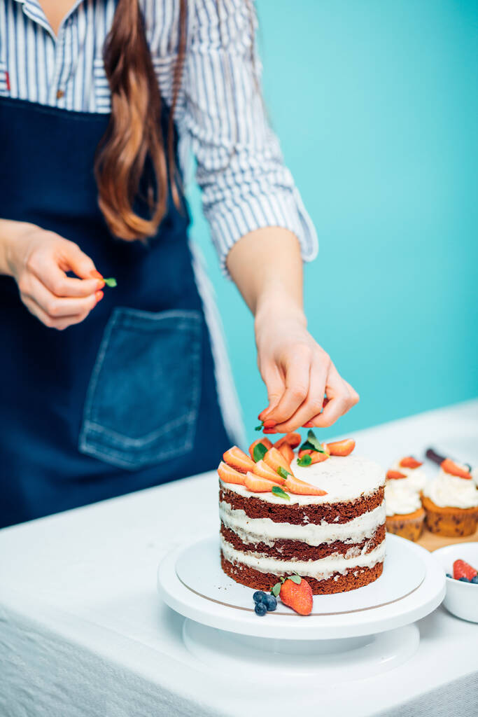 Женщина украшает вкусный торт - Фото, изображение