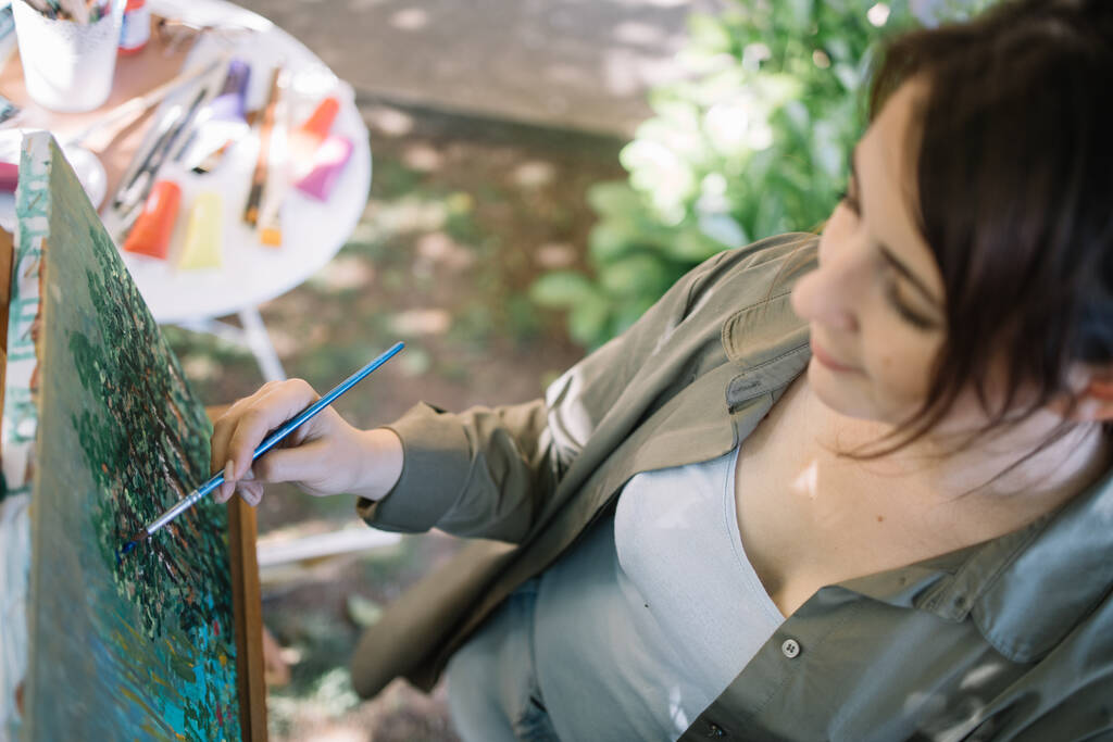 Kadın sanatçı, açık hava atölyesinde el boyaması yapıyor. - Fotoğraf, Görsel