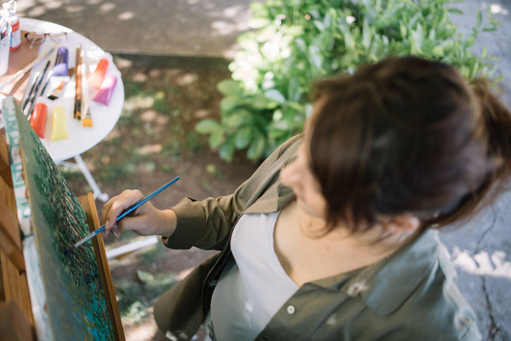 Vista de ángulo alto de la mujer sosteniendo pincel de pintura y pintura
 - Foto, imagen