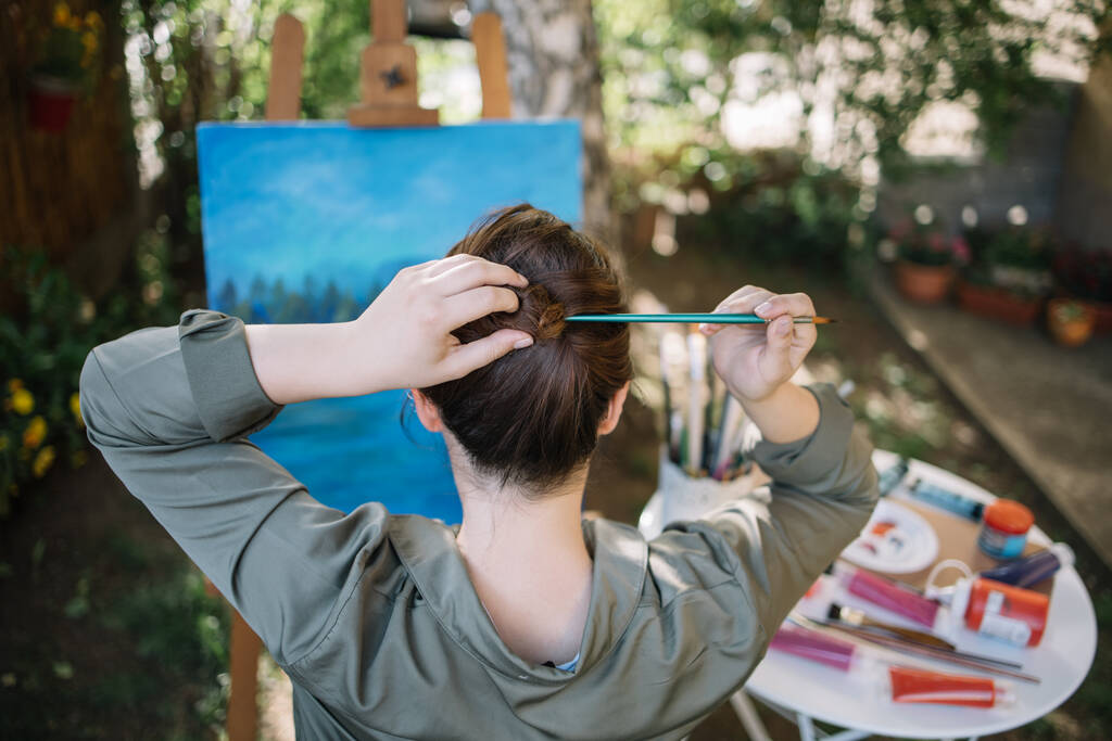 Жіночий художник робить зачіску з пензлем на відкритому повітрі
 - Фото, зображення