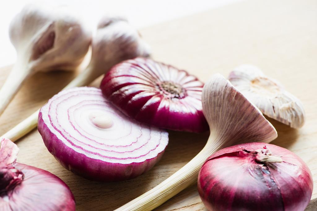 close up view of red onion and garlic on wooden cutting board isolated on white - Photo, Image