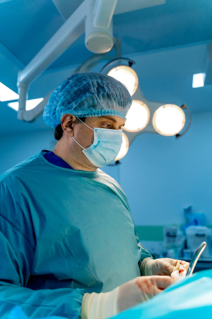 Chirurg bei der chirurgischen Operation in einem hellen, modernen Operationssaal. Operationssaal. Moderne Geräte in der Klinik. Notaufnahme. - Foto, Bild