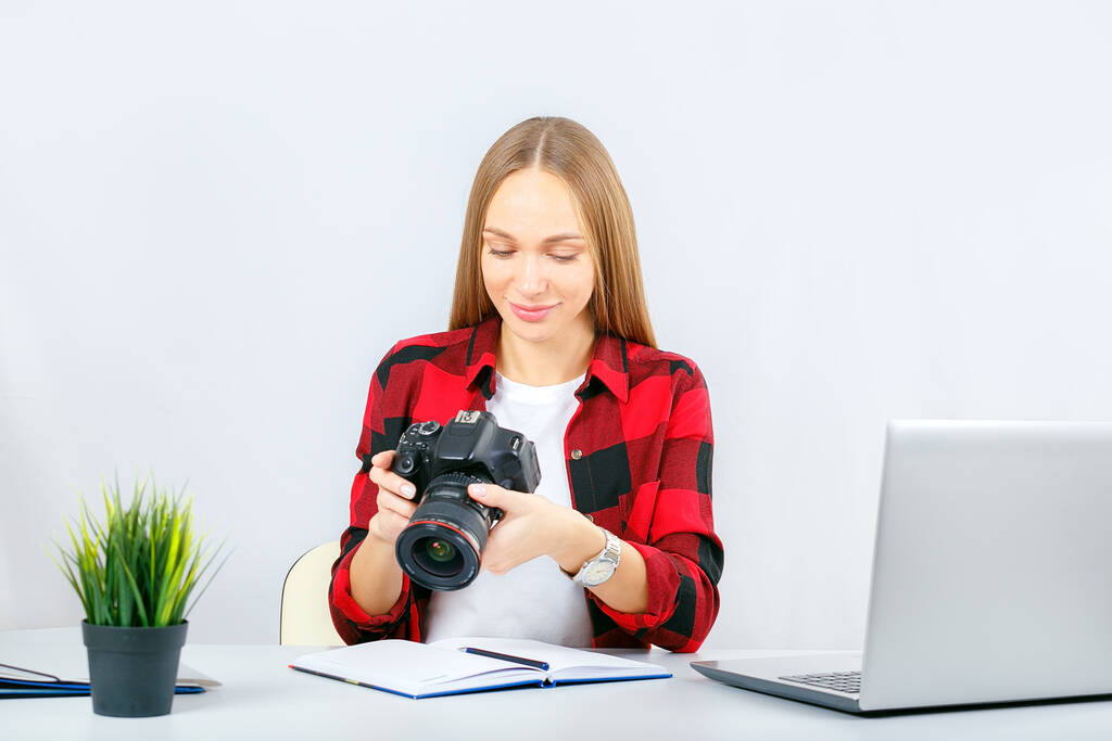 Jonge fotograaf of grafisch ontwerper aan het werk in kantoor of thuis. Vrouw op kantoor op zoek naar fotocamera.  - Foto, afbeelding