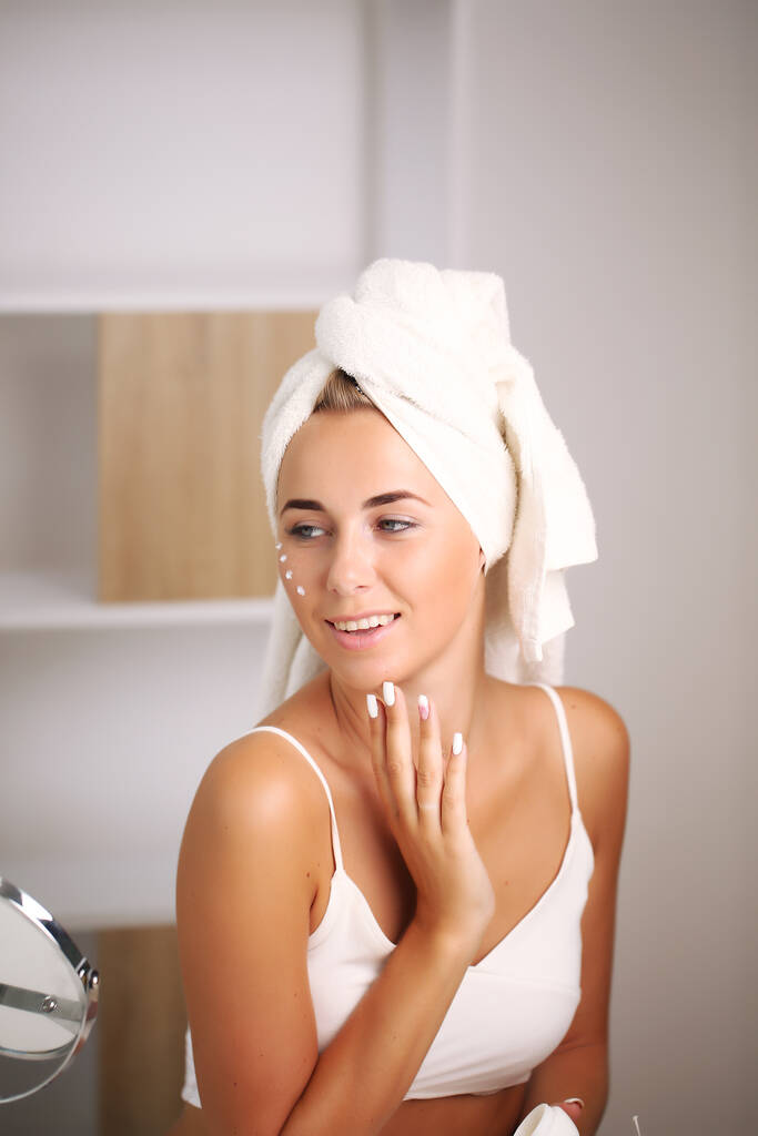 retrato de uma bela mulher aplicando creme facial para cuidados com a pele - Foto, Imagem