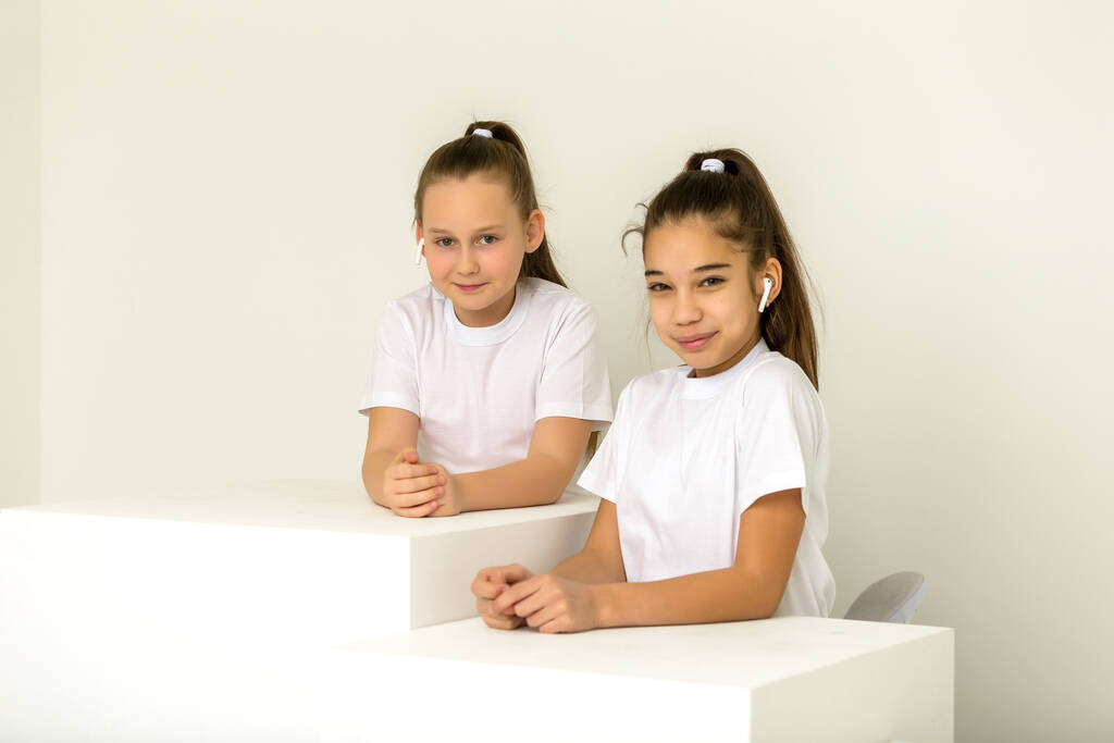 Дві маленькі дівчата позують в студії на білих кубиках
 - Фото, зображення
