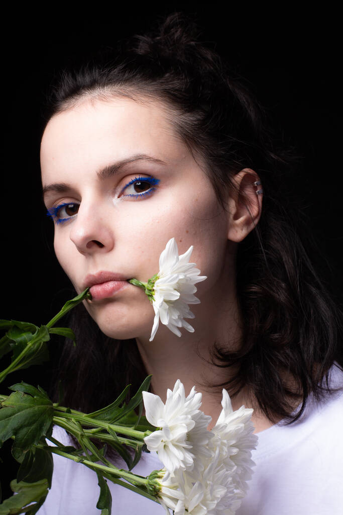 mujer comiendo flores blancas sobre fondo negro - Foto, Imagen