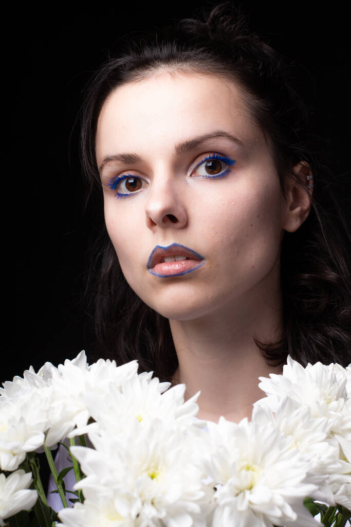 μοντέρνα γυναίκα με μπλε μακιγιάζ ματιών και το σημάδι ελέγχου στα χείλη, πορτρέτο γκρο πλαν, μαύρο φόντο - Φωτογραφία, εικόνα