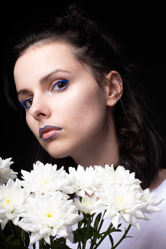 Frau mit modelliertem Aussehen, Porträt mit weißen Blumen auf schwarzem Studiohintergrund - Foto, Bild