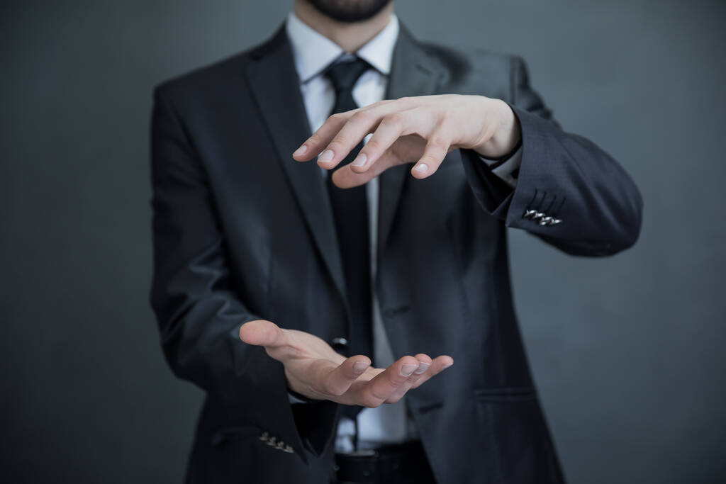 Liikemies tyhjä käsi esittää jotain harmaa backgroun - Valokuva, kuva