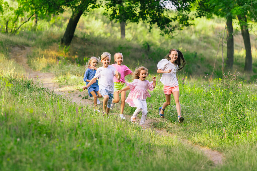 夏の日差しの中で草原を走る子供たち - 写真・画像