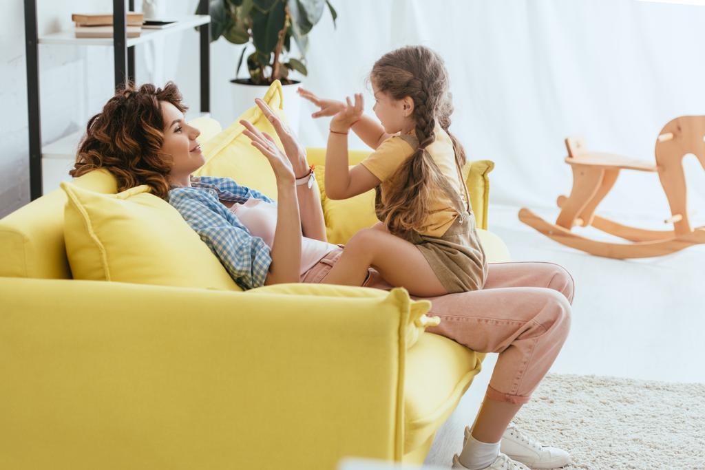niñera feliz y el niño jugando juego de pat-a-cake mientras se divierten en el sofá - Foto, imagen