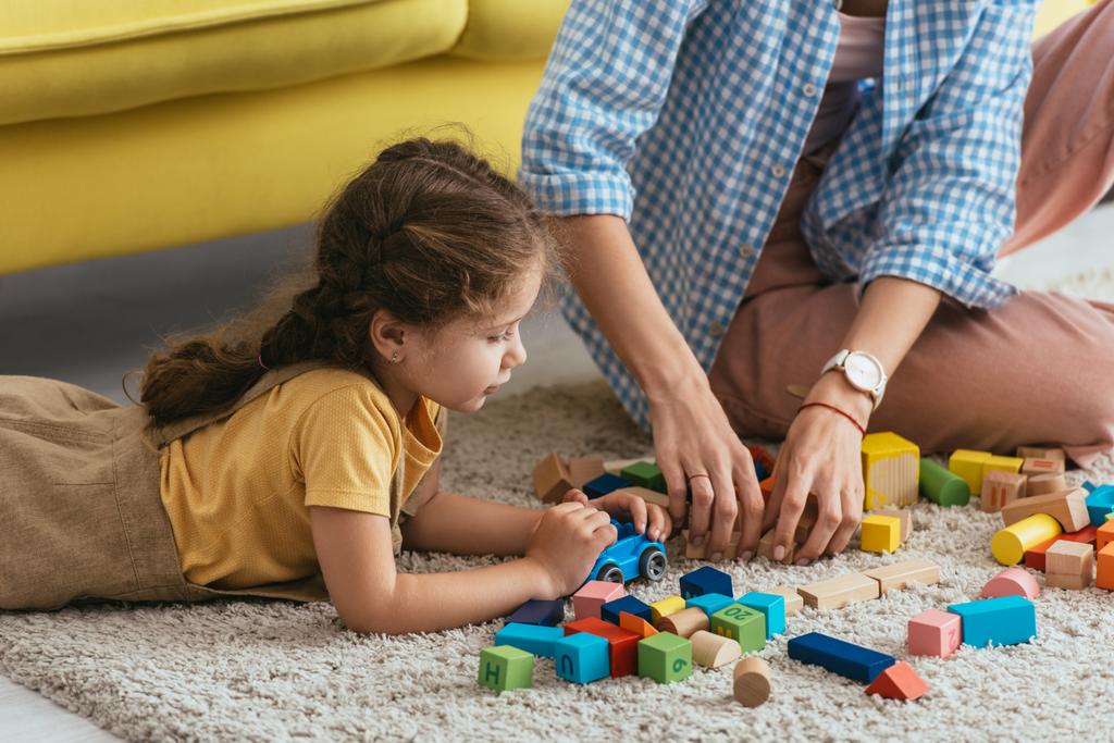 corte vista de babá e criança brincando com blocos multicoloridos de chão
 - Foto, Imagem