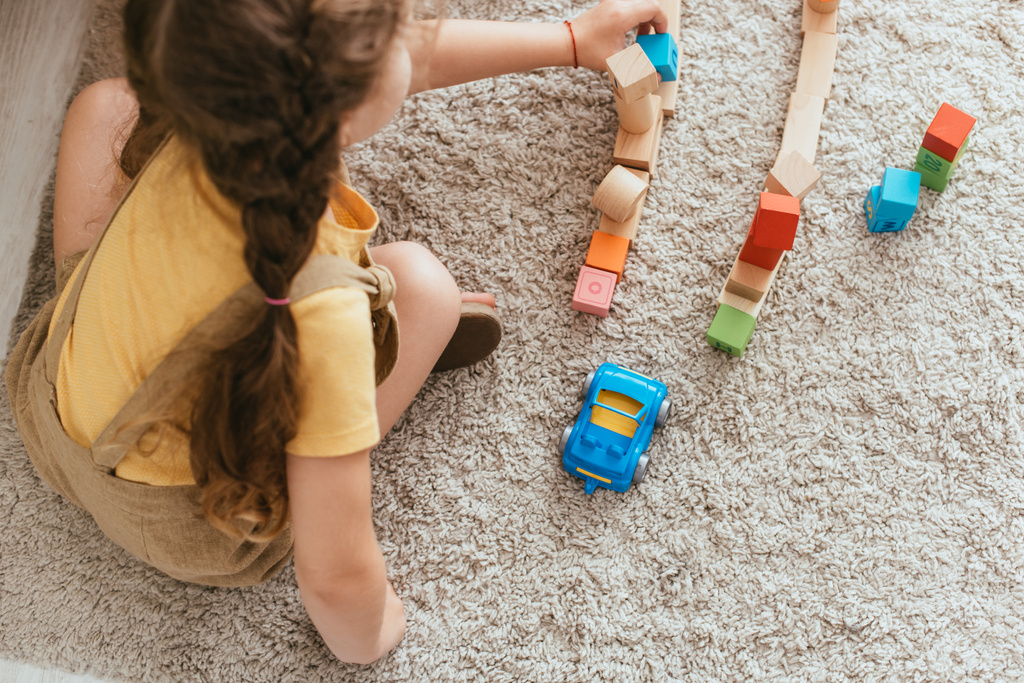 vista dall'alto del bambino seduto sul pavimento e che gioca con blocchi multicolori - Foto, immagini