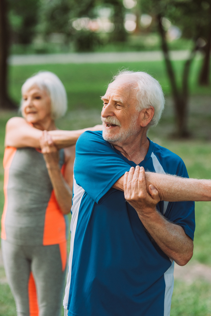 Селективный акцент на веселых тренировках для пожилых мужчин возле жены в парке  - Фото, изображение