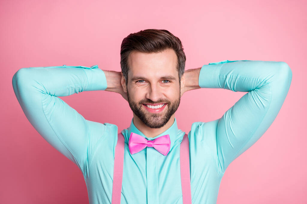 Φωτογραφία του όμορφος άντρας macho μόδα ρούχα στολή toothy ακτινοβολούν χαμόγελο κρατήστε τα χέρια πίσω από το κεφάλι καλή διάθεση φορούν τιράντες πουκάμισο πλώρη γραβάτα απομονωμένο παστέλ ροζ χρώμα φόντο - Φωτογραφία, εικόνα