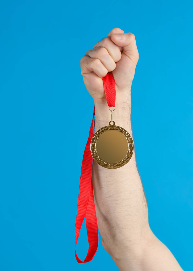 Een man met een gouden medaille op een blauwe achtergrond. Ruimte voor ontwerp - Foto, afbeelding