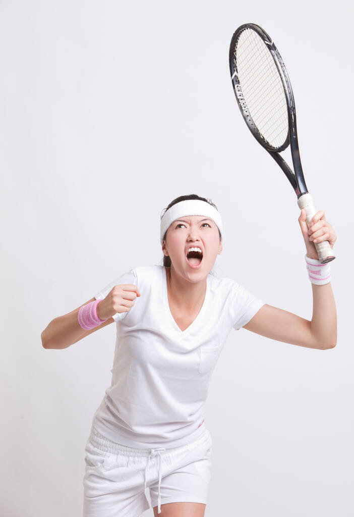 Young female tennis player with racket cheering against white background - Photo, Image
