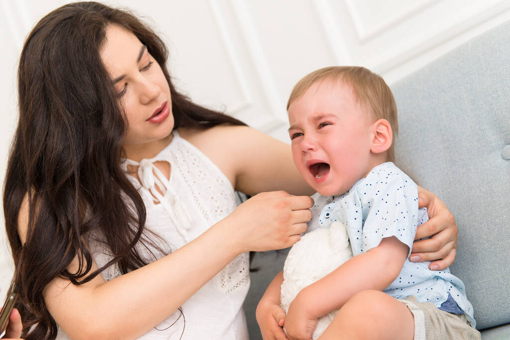 triste bébé pleurant près de la femme - enfant en colère avec la mère sur le canapé  - Photo, image